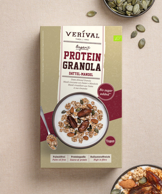 Eine Packung Verival Bio Bio Dattel-Mandel Protein-Müsli, auf deren Vorderseite eine Schüssel mit dem Müsli zu sehen ist, das mit Joghurt vermischt und mit verstreuten Kürbiskernen garniert ist, wodurch der pflanzliche Proteingehalt hervorgehoben wird.