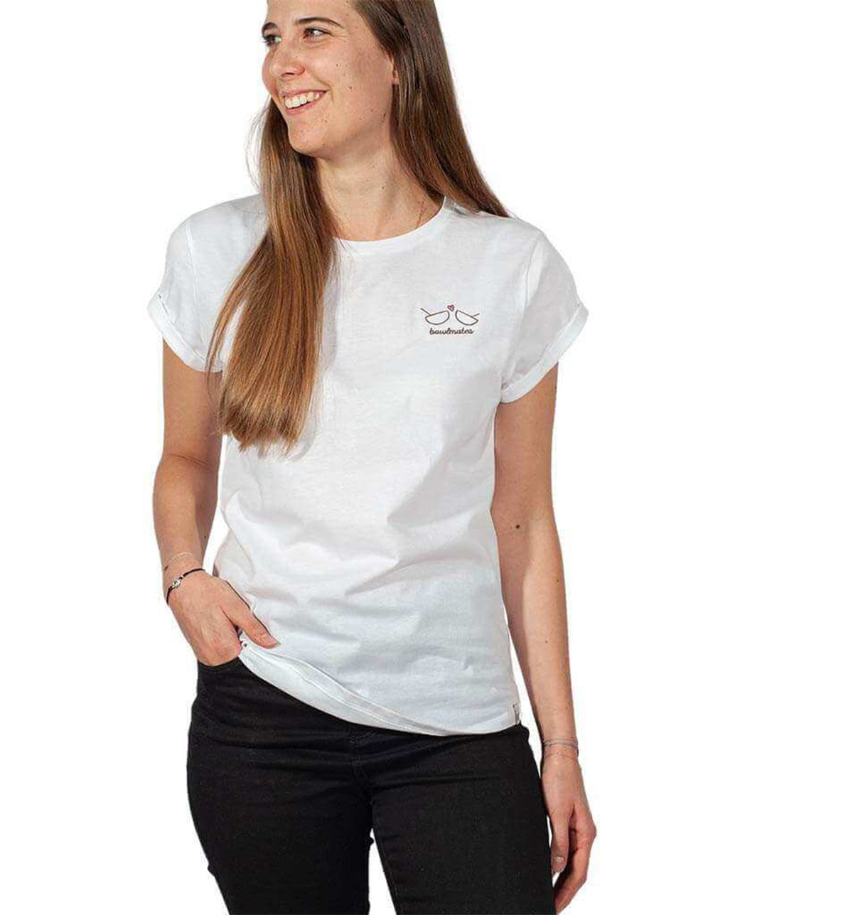 Eine Frau mit langen Haaren trägt das T-Shirt Bowlmates von Verival Bio mit kleinem Logo. Sie lächelt und blickt in ihrer schwarzen Hose vor schlichtem weißen Hintergrund zur Seite.